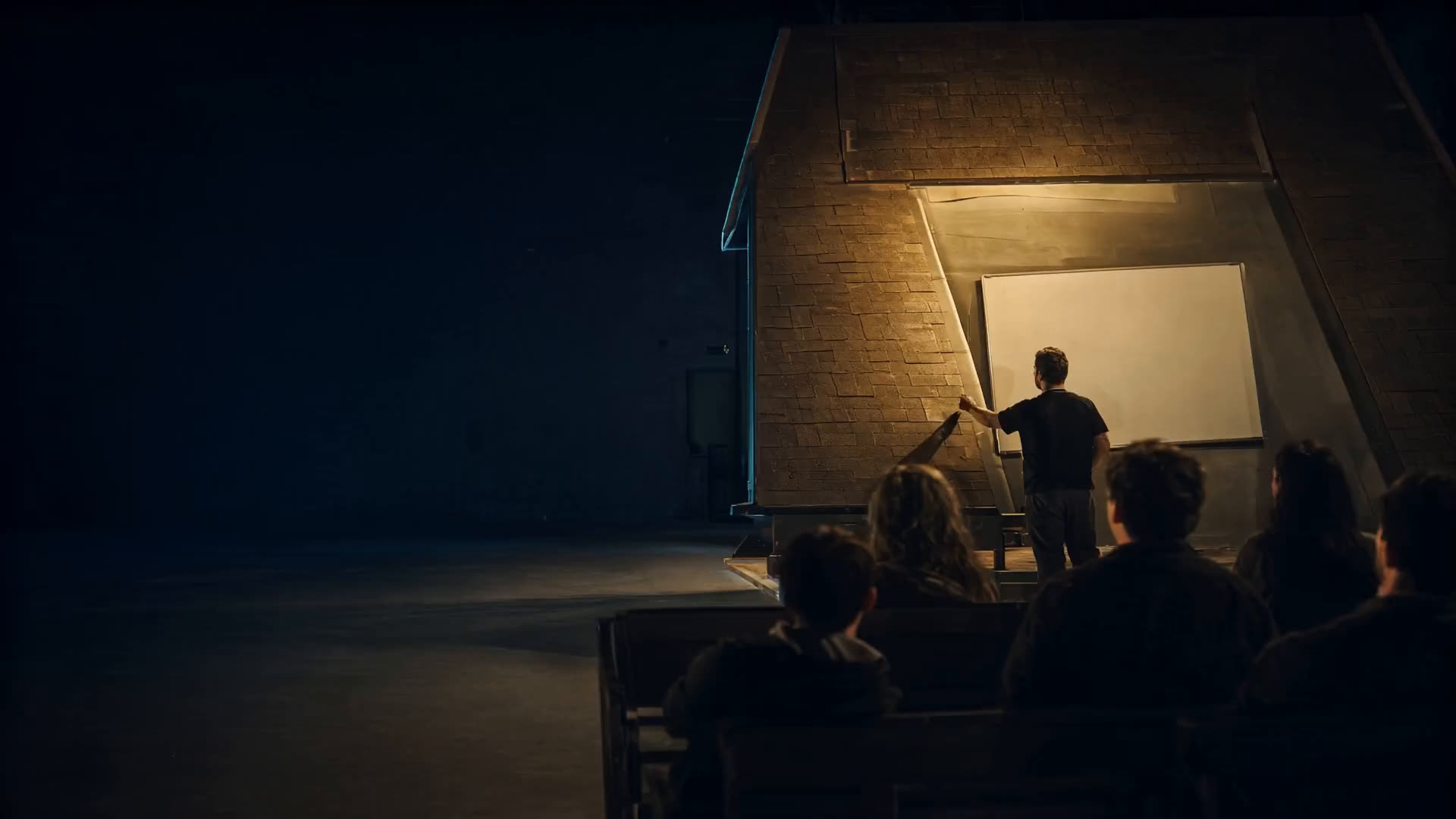 A training room with a roof mock-up, people seen from behind