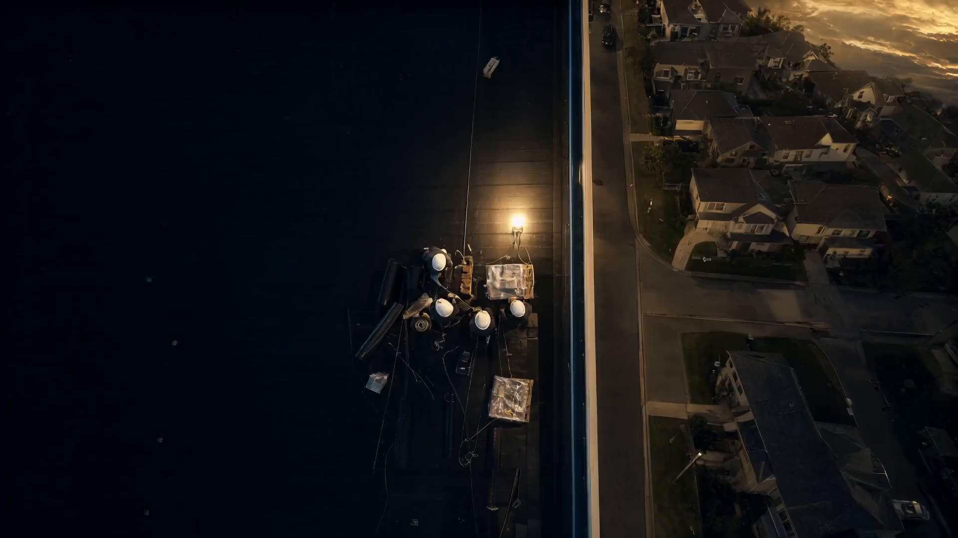 A crew working on a commercial roof next to homes, seen from above