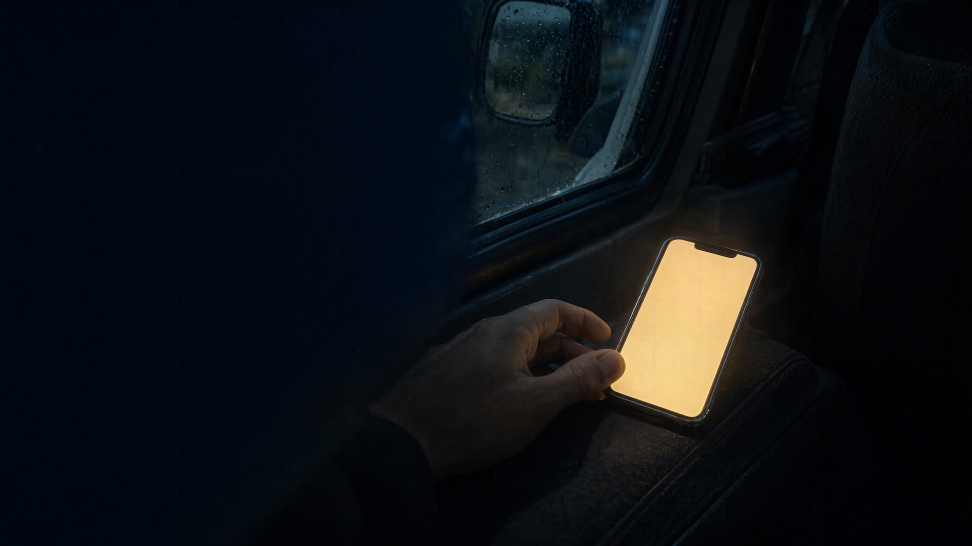 A phone lighting up inside a truck in the rain
